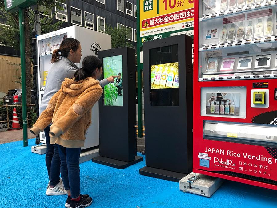 駐車場に設置したデジタルサイネージと見る人